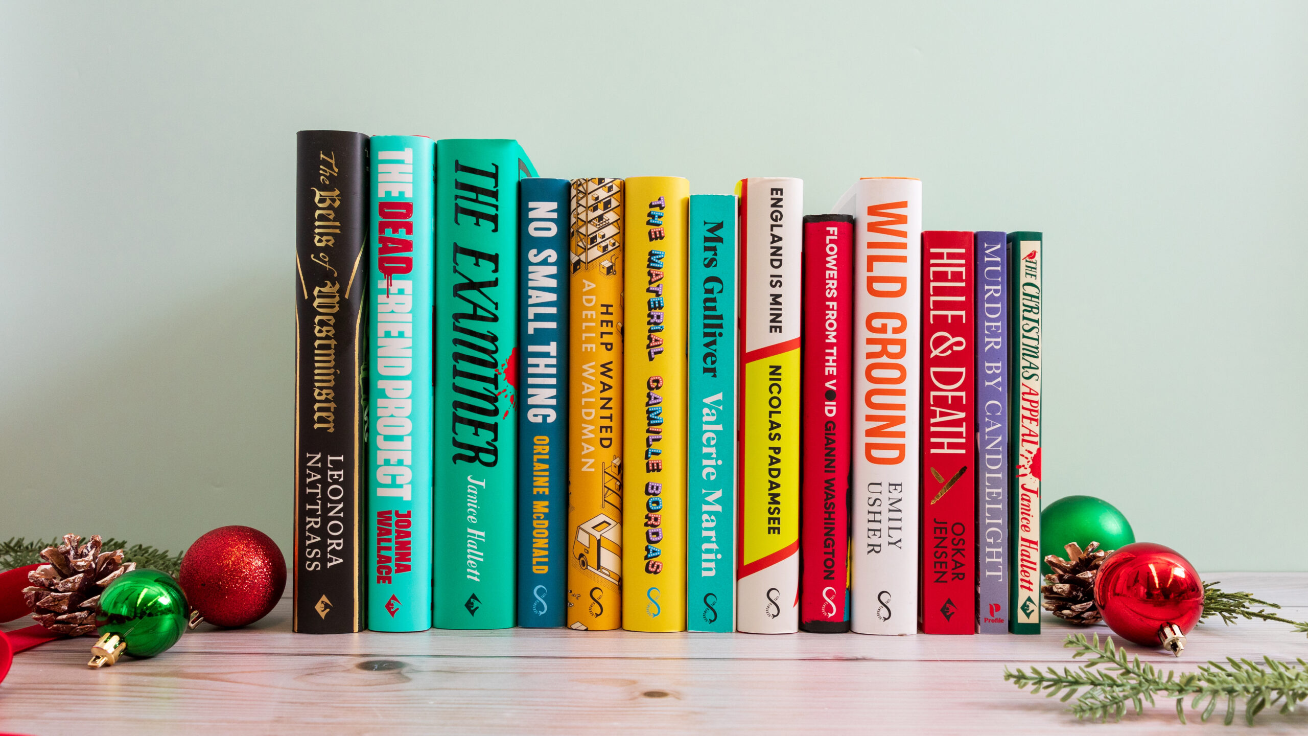 A photograph with 13 books facing spine-out. Christmas decorations surround the outside.